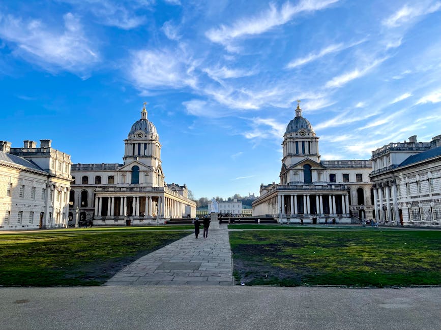 A panoramic view of a historic white palace with classical architecture, featuring columns and domed towers, situated in a large landscaped park with well-maintained grassy areas and walking paths. The palace is set against a backdrop of modern high-rise office buildings and skyscrapers in the city skyline of Greenwich. The scene is illuminated by natural daylight, and the park appears clean and orderly, with a few people strolling or relaxing on the grass, reflecting maintenance and tidiness. The image may include visible tools or signs of recent cleaning activities, emphasizing thorough surface cleaning, deep cleaning, and sanitisation by Greenwich Carpet Cleaning, highlighting its domestic cleaning services in the Greenwich area.